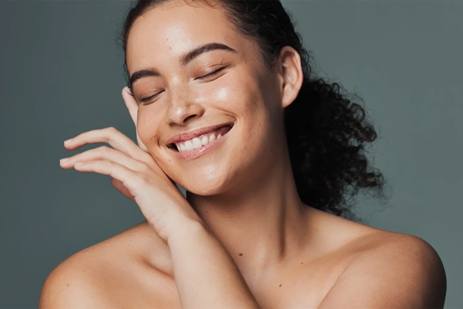Smiling woman touching her soft, clean skin after a relaxing facial