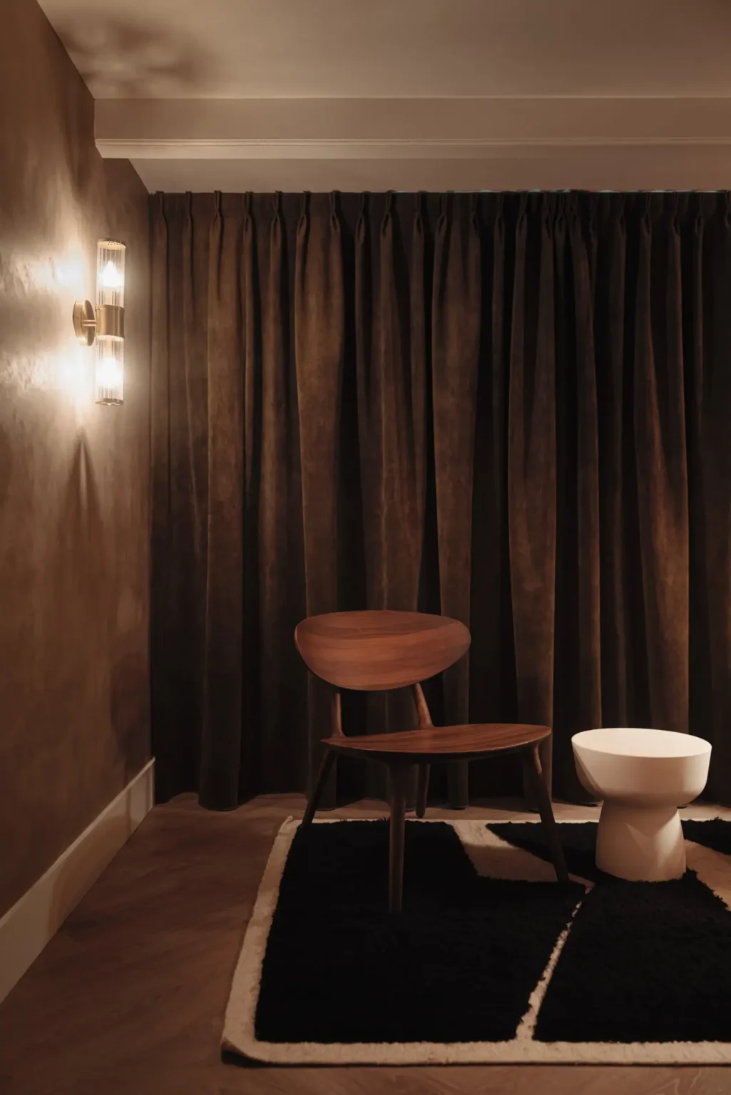 Corner of the treatment room at Her Healing Massage & Wellness Studio, with a wooden chair and warm lighting
